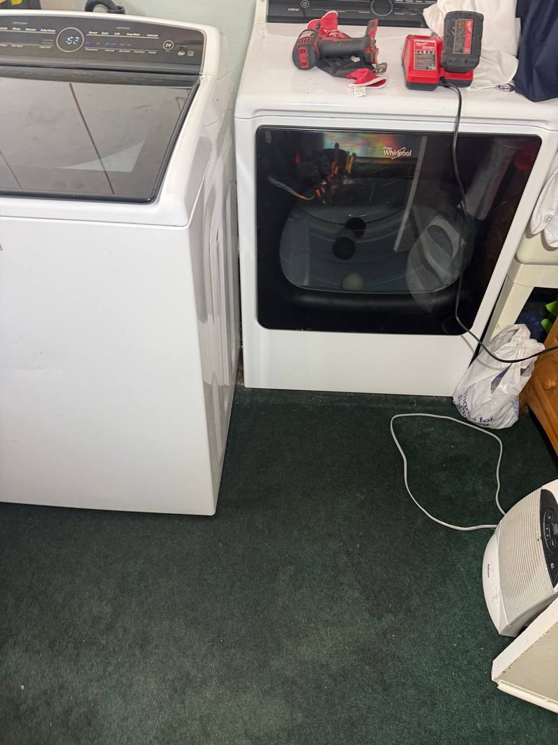 Whirlpool dryer with the door open and a drill on top during a drum repair