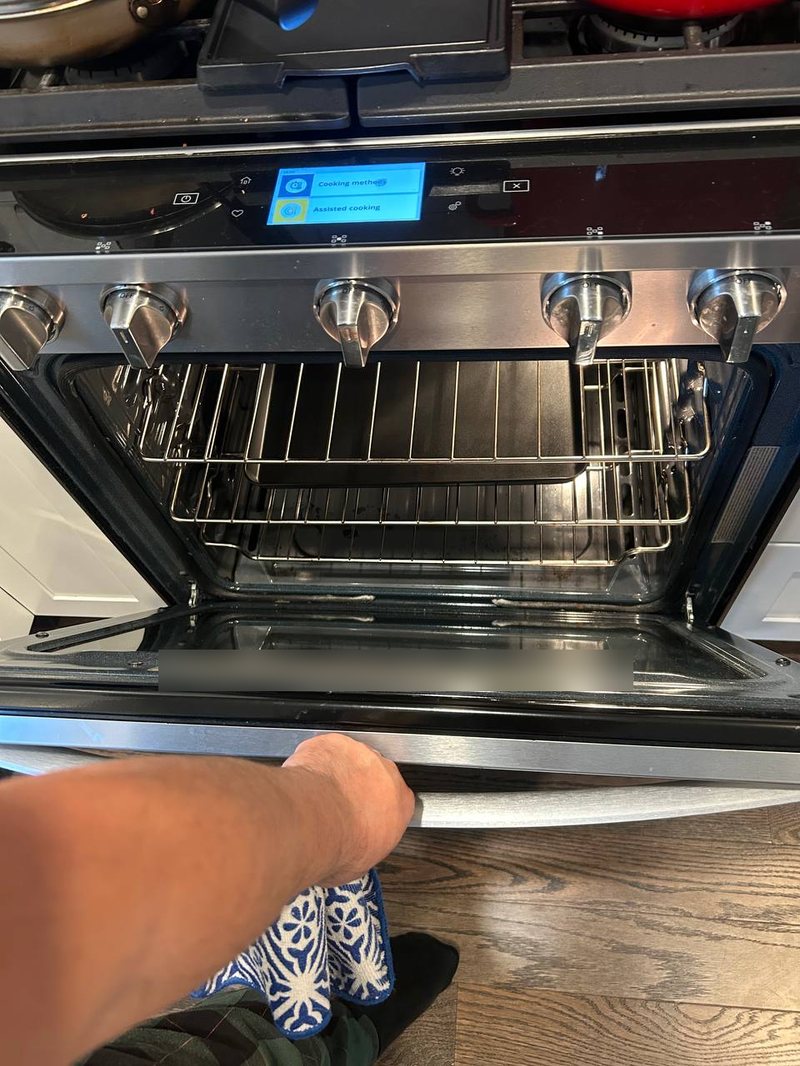 Gas range with the oven door open and the touch display lit during an igniter and temperature check